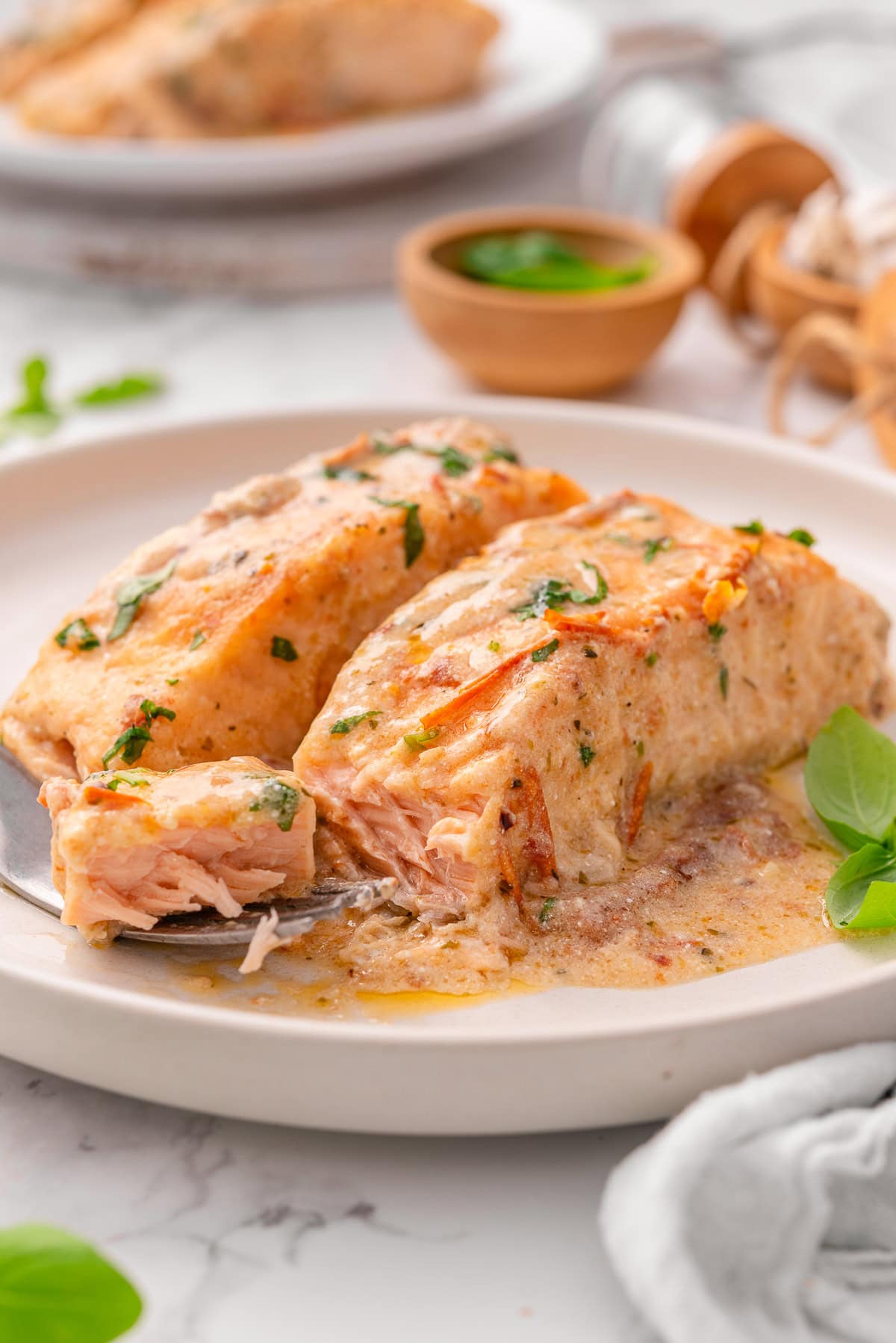 Side view of marry me salmon flaked with a fork on a plate.