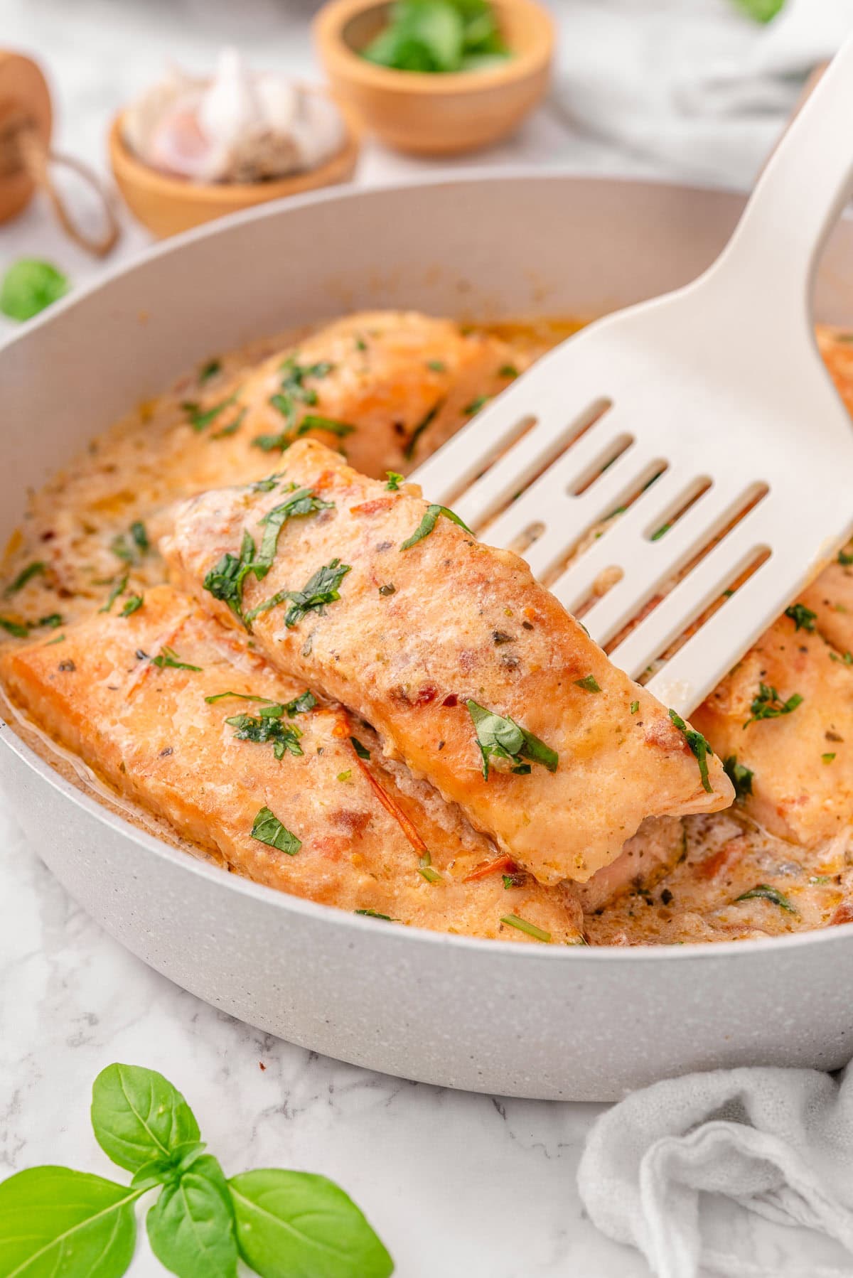Marry me salmon on a spatula in a skillet.