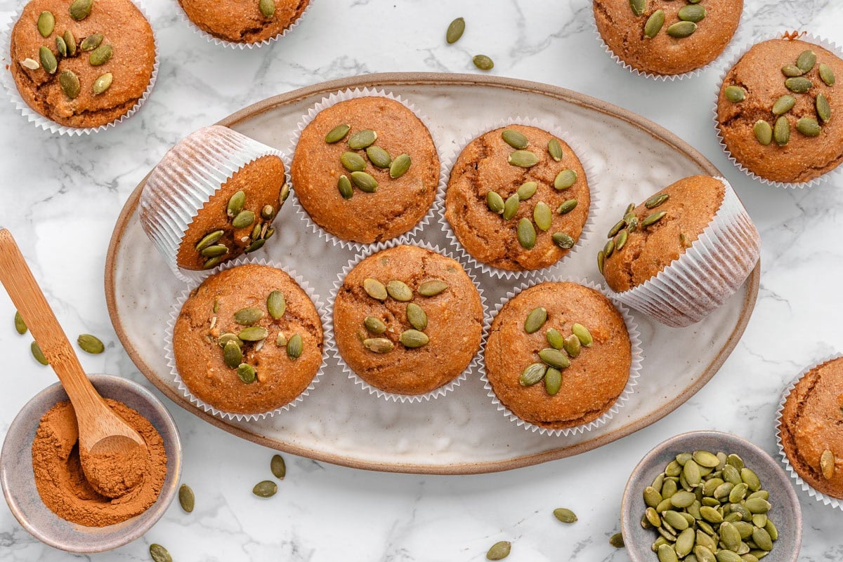 Kodiak pumpkin muffins on a plate. Pumpkin seeds and spice in bowls.