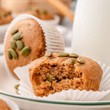 Kodiak pumpkin muffins in parchment paper liners and milk in a jug.