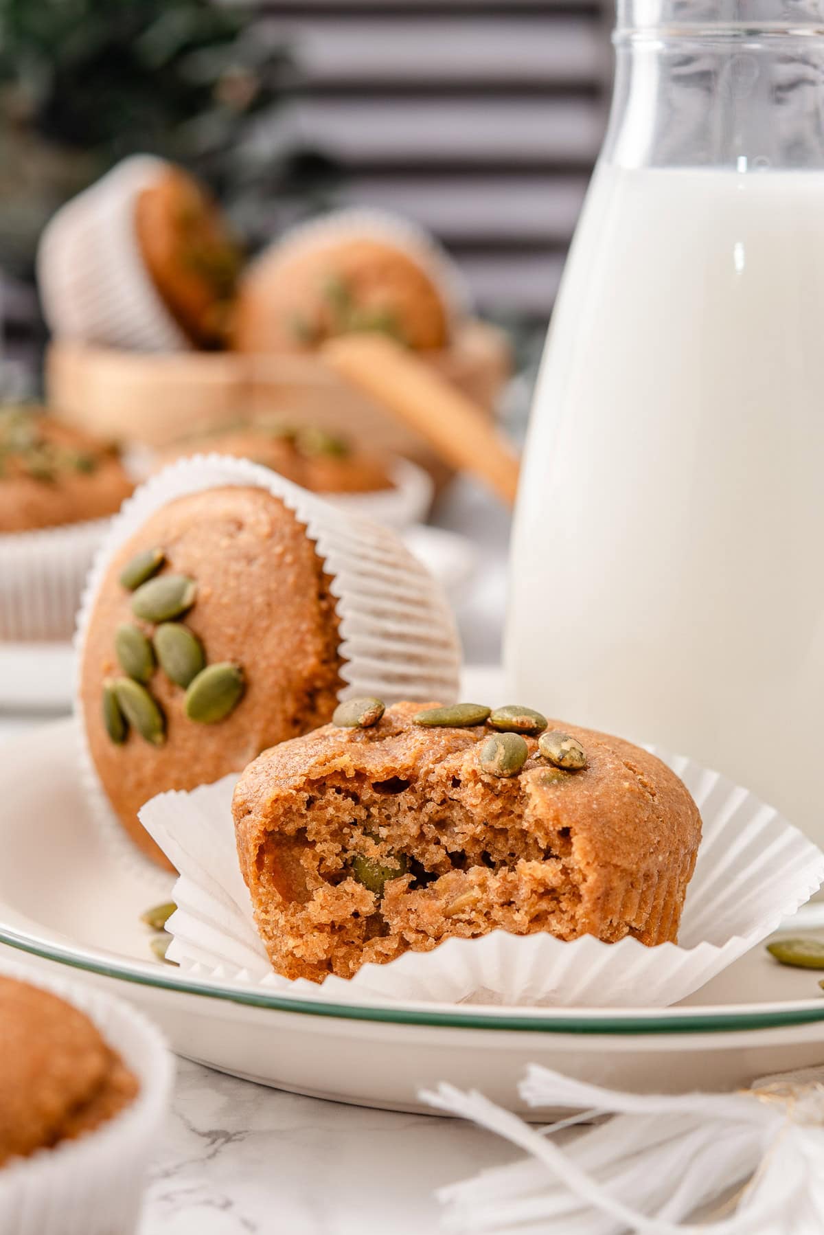 Kodiak pumpkin muffins in parchment paper liners and milk in a jug.