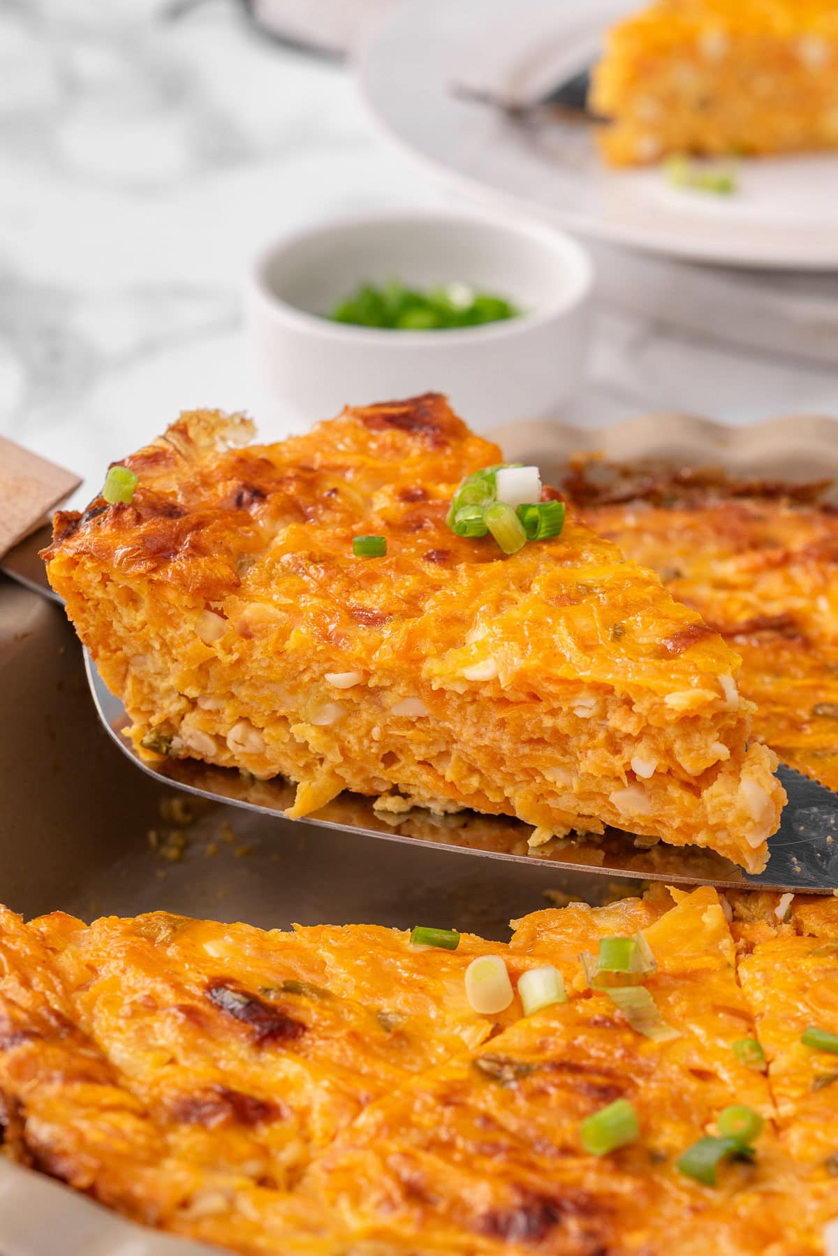 A slice of crustless cottage cheese sweet potato quiche on a serving spoon.