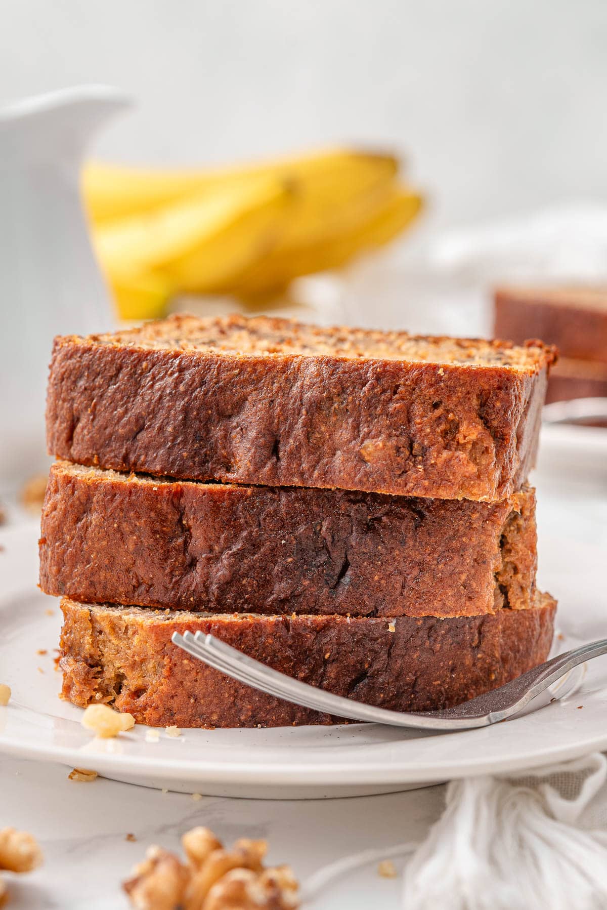 Three slices of kodiak banana bread on a plate with a fork.