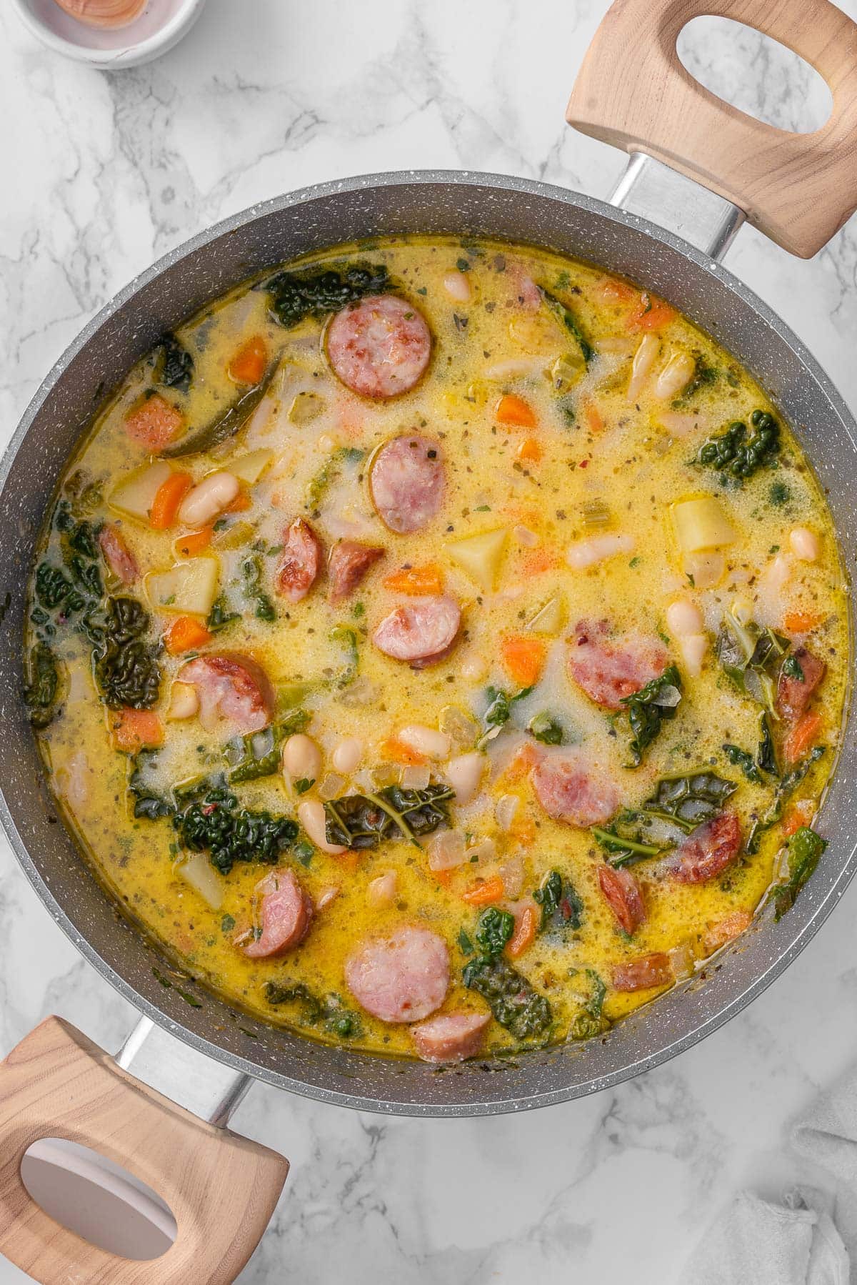 Sausage kale white bean soup in a pot.