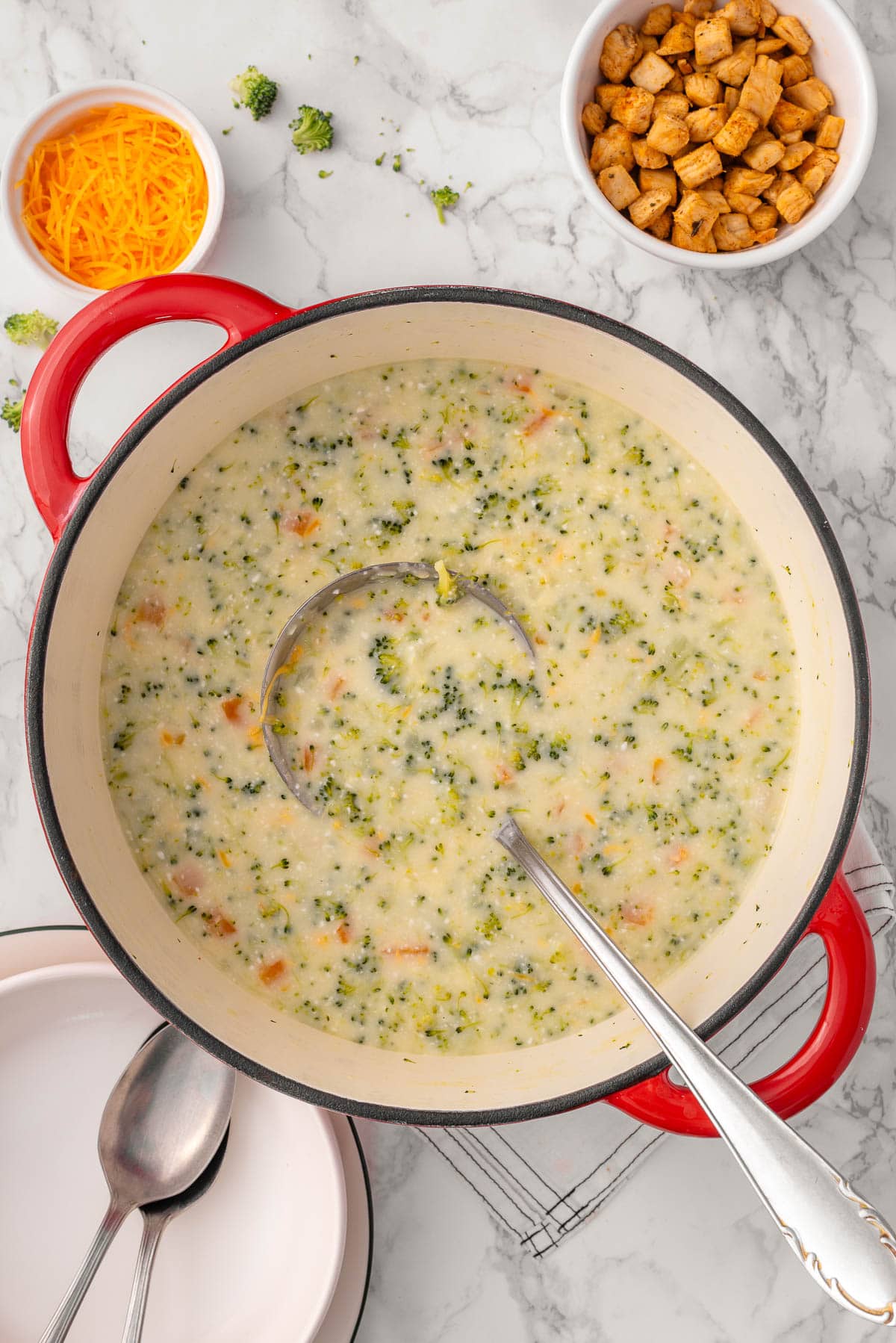 High protein broccoli cheddar soup and ladle in red pot.