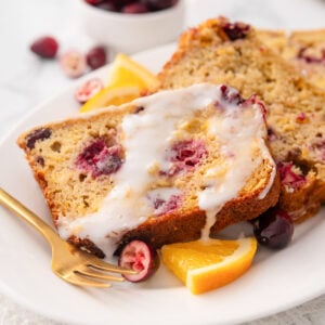 Cranberry orange bread slices with glaze on a plate.