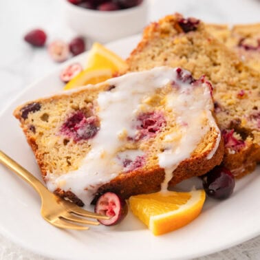 Cranberry orange bread slices with glaze on a plate.