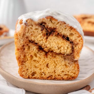 Greek yogurt cinnamon roll bread with frosting on a plate.