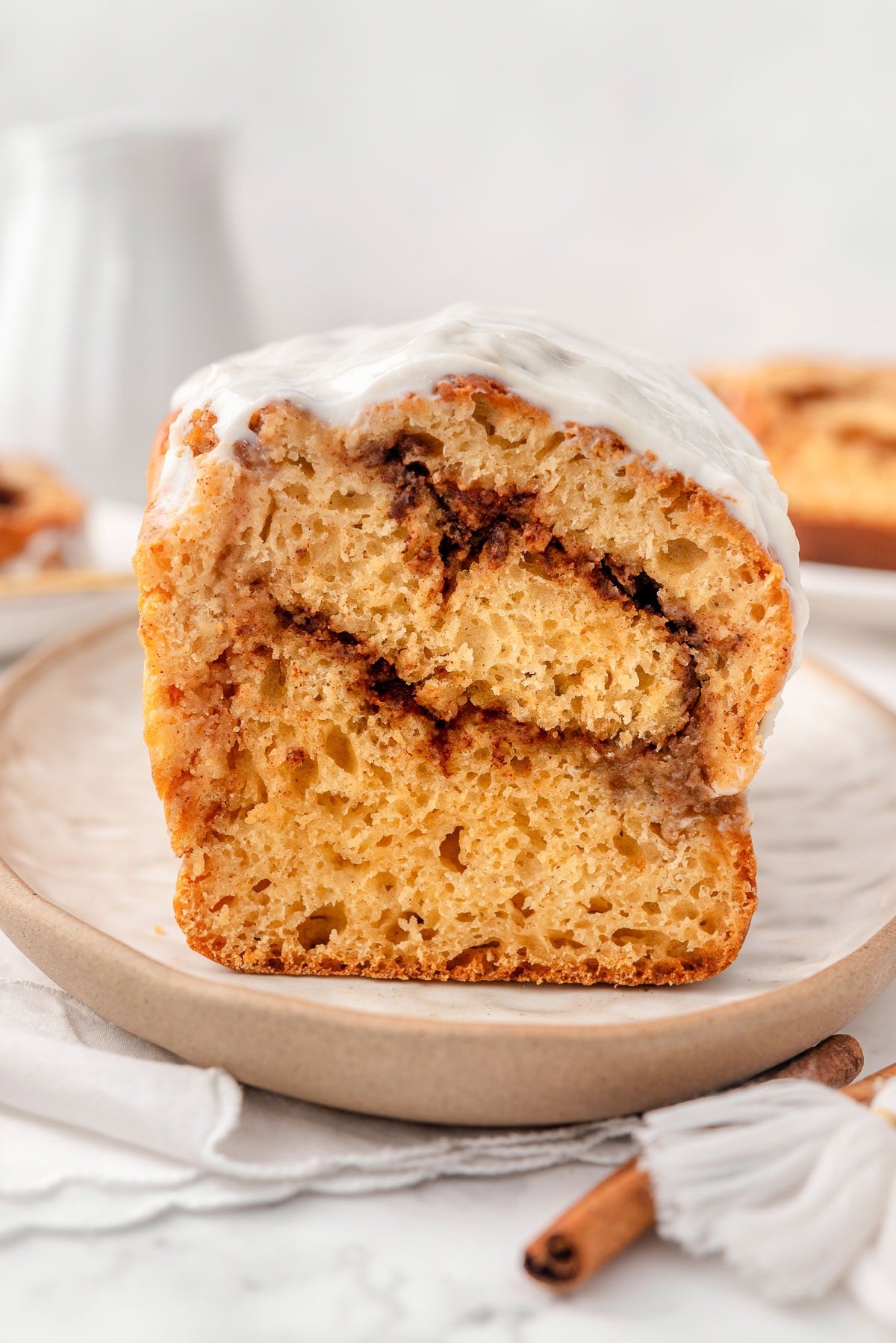 Greek yogurt cinnamon roll bread with frosting on a plate.