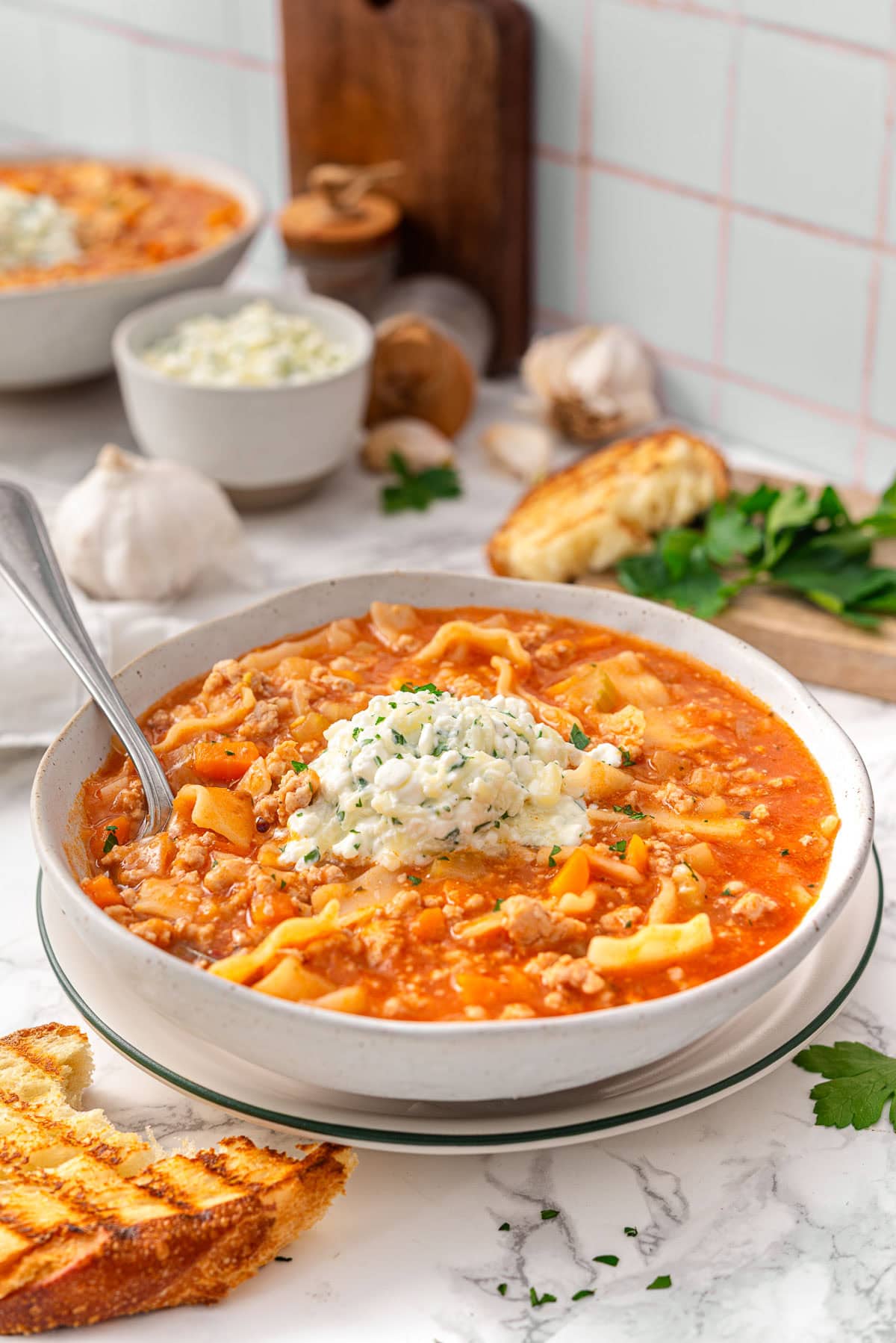 High protein lasagna soup with dollop of cheese mixture in a bowl.