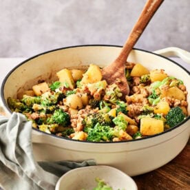 Ground turkey and potatoes with broccoli in a pot with a spoon.
