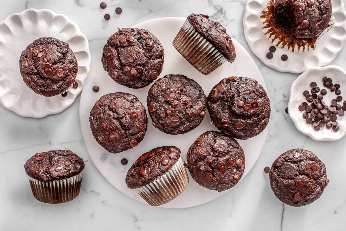Hidden veggie chocolate muffins on plates and chocolate chips in bowls.