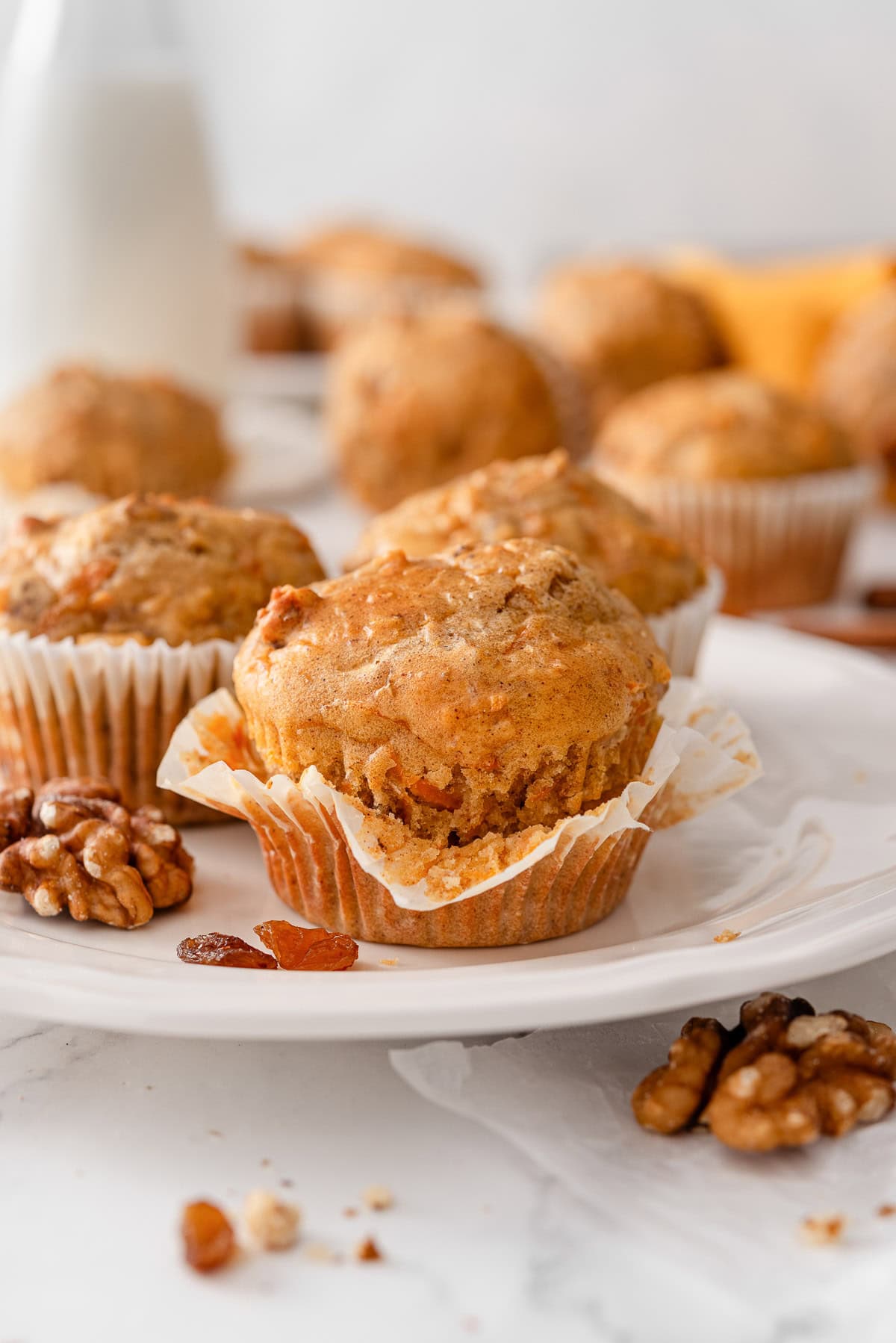 Cottage cheese carrot cake muffins in wrappers on a counter.