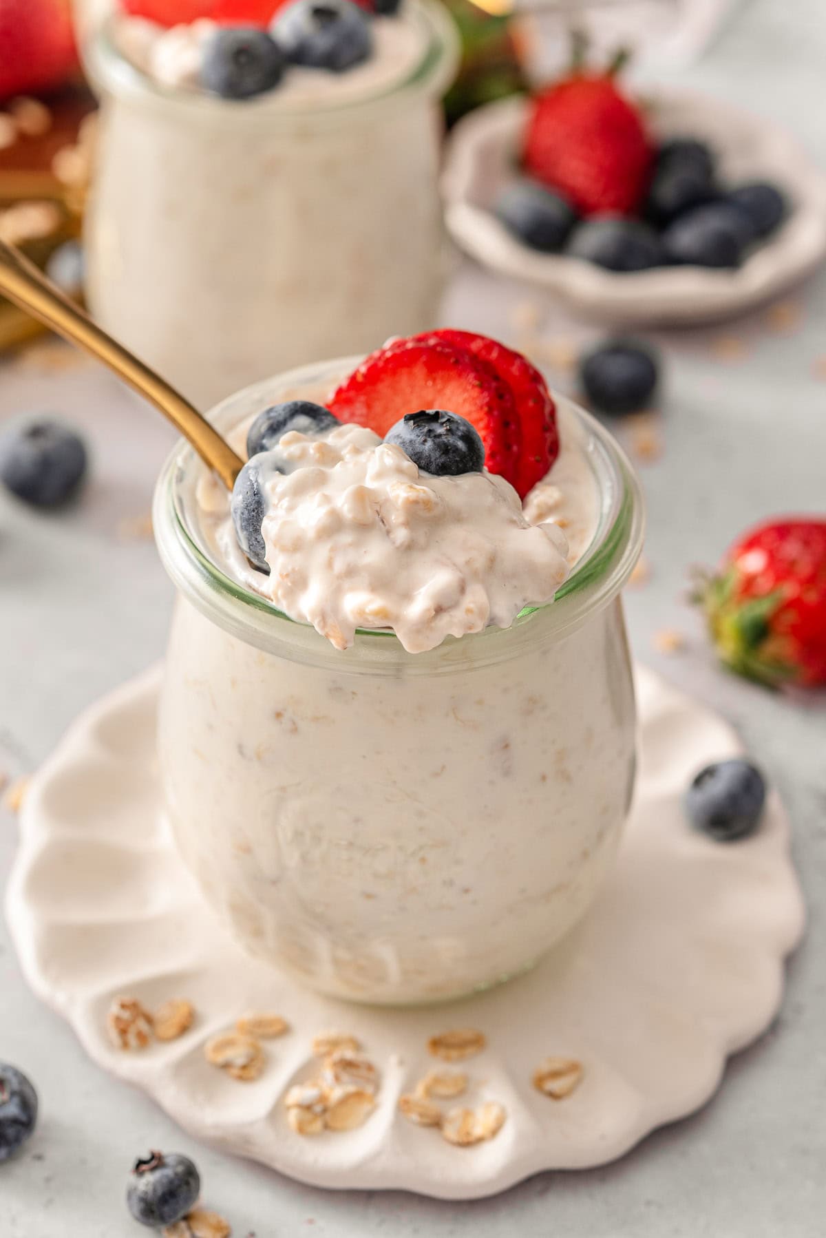Scooping greek yogurt overnight oats with a spoon from a jar.