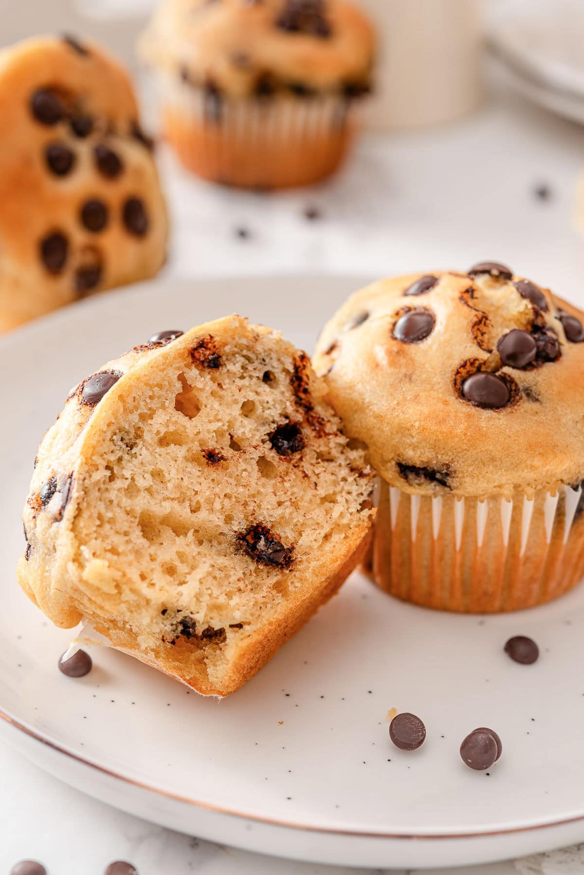 Sliced in half greek yogurt muffin next to another muffin on a plate.