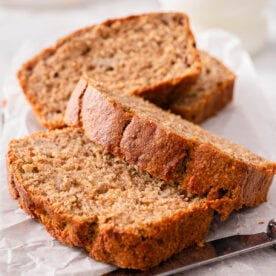 Sliced healthy banana bread and knife on parchment paper.