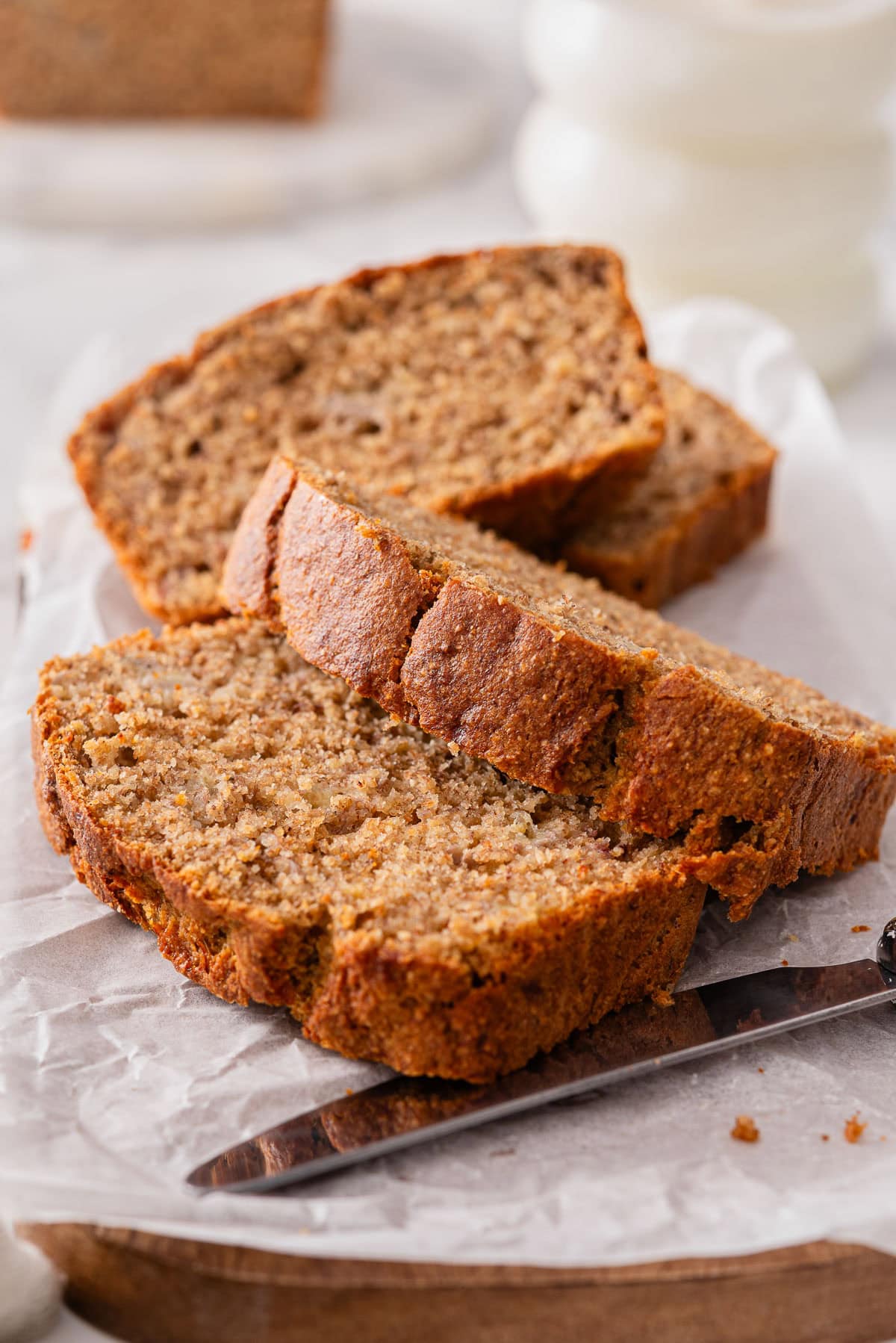 Sliced healthy banana bread and knife on parchment paper.