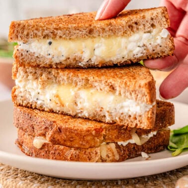 Cottage cheese grilled cheese cut in half stacked on a plate.