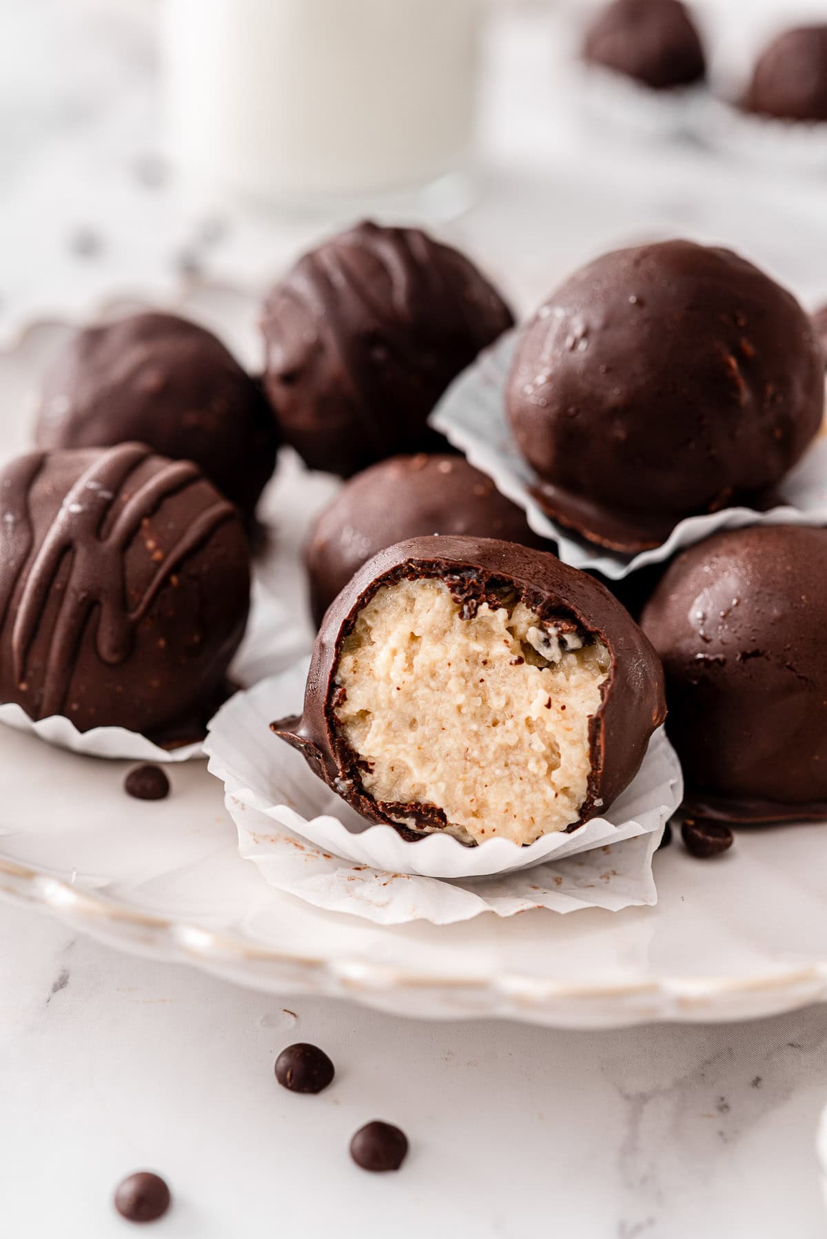 Greek yogurt protein ball taken a bite of and showing texture inside. With more protein balls on a plate.
