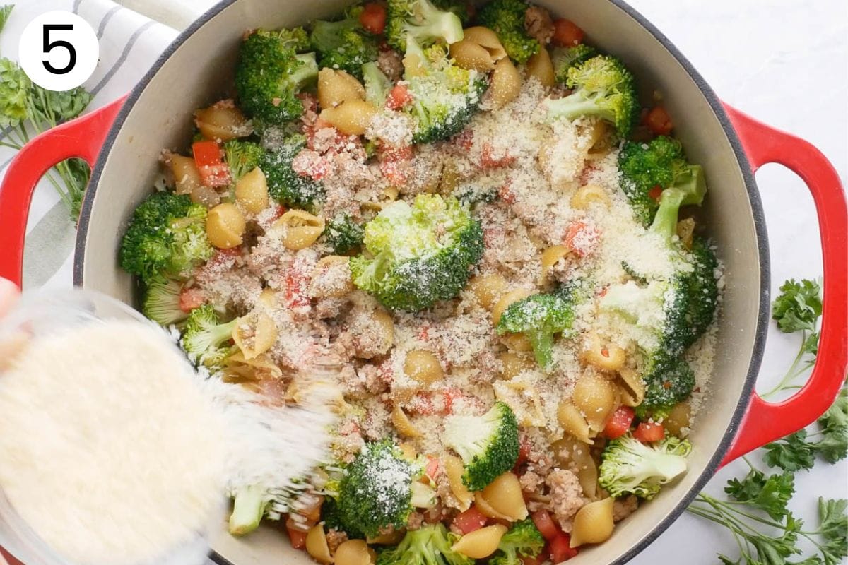 Sprinkling Parmesan cheese on ground turkey and broccoli.