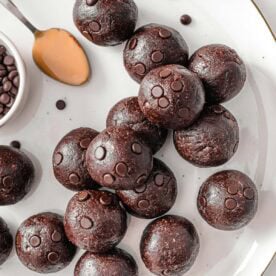 Chocolate protein balls with a spoonful of peanut butter on a plate.