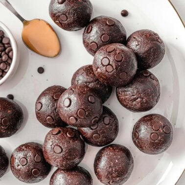 Chocolate protein balls with a spoonful of peanut butter on a plate.