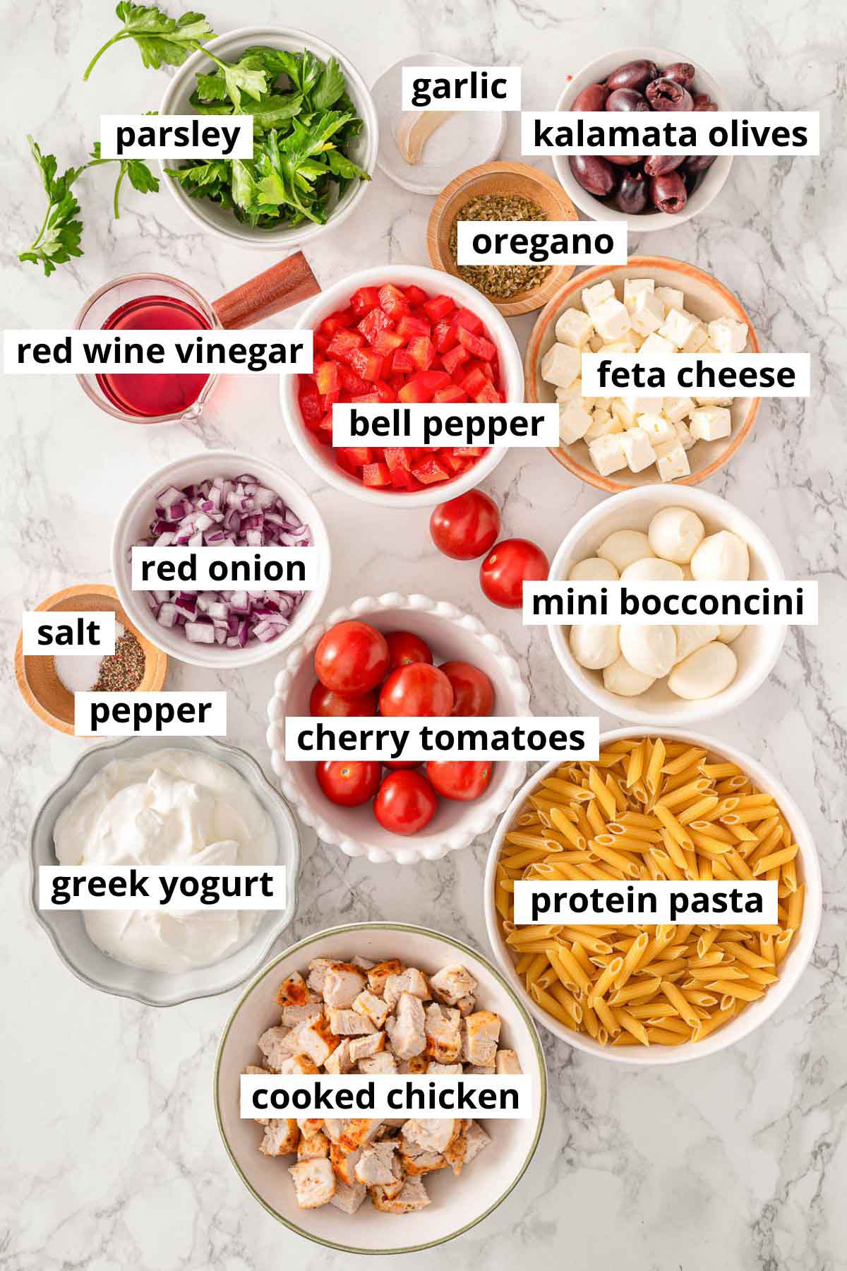 Protein pasta, cooked chicken, cherry tomatoes, bocconcini, red onion, parsley, olives, feta, vinegar, garlic, salt, pepper, greek yogurt, dried oregano, bell pepper.